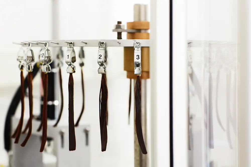 Brunette strands of hair are lined up on a hair robot.