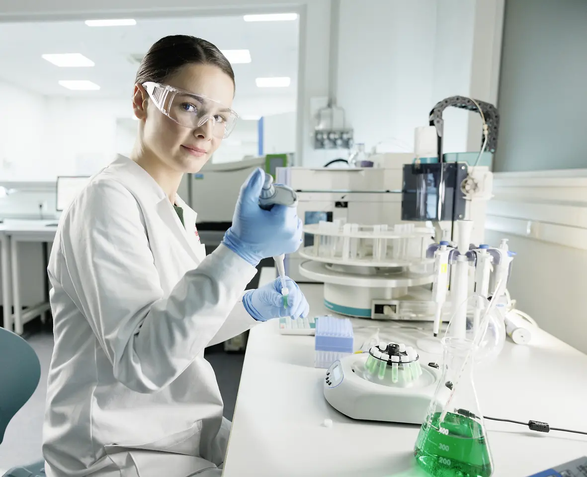 Una científica está trabajando en un laboratorio, con bata y gafas de seguridad.