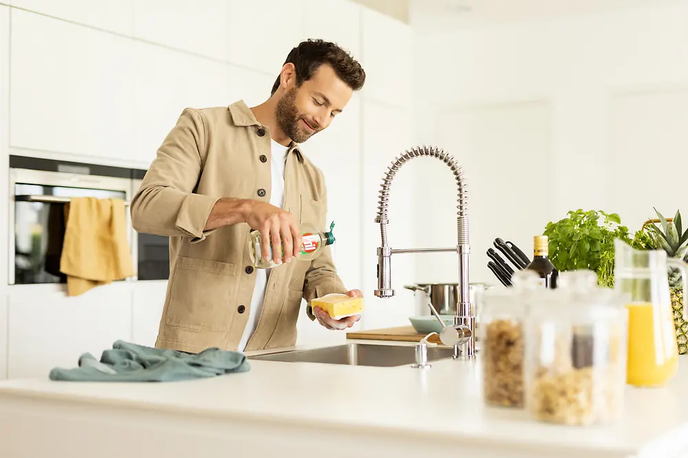 Hombre en la cocina lavando los trastes. 