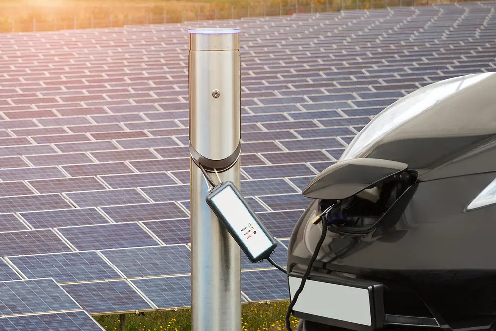 Coche eléctrico frente a un campo de panel solar.