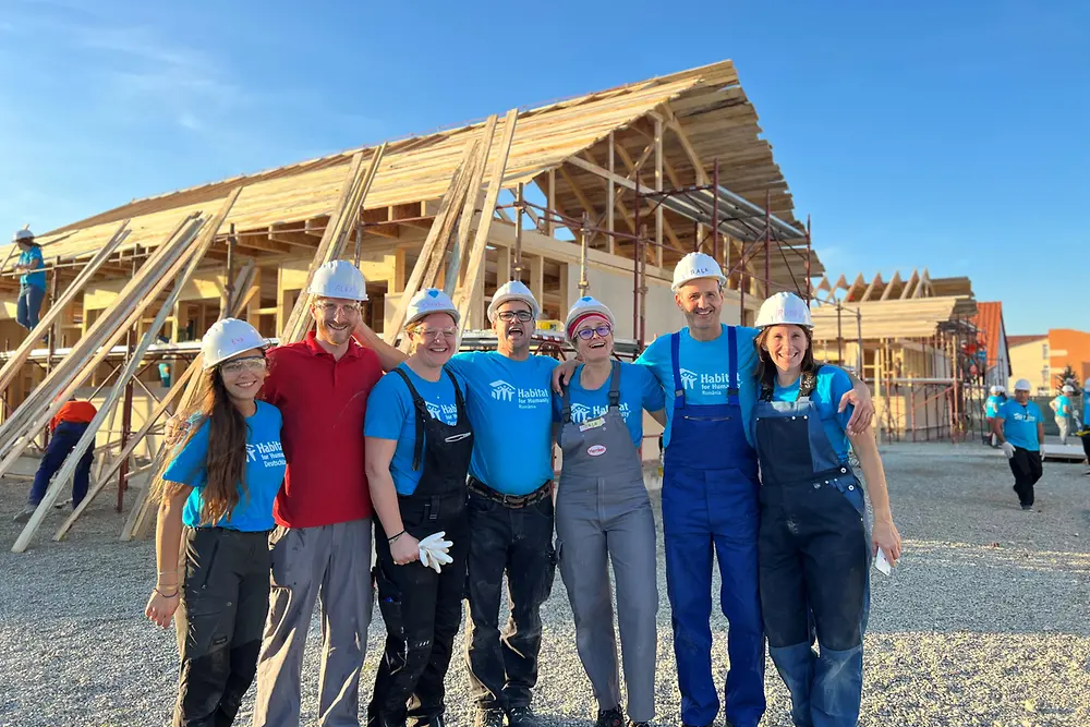 Voluntarios abrazados frente a construcción