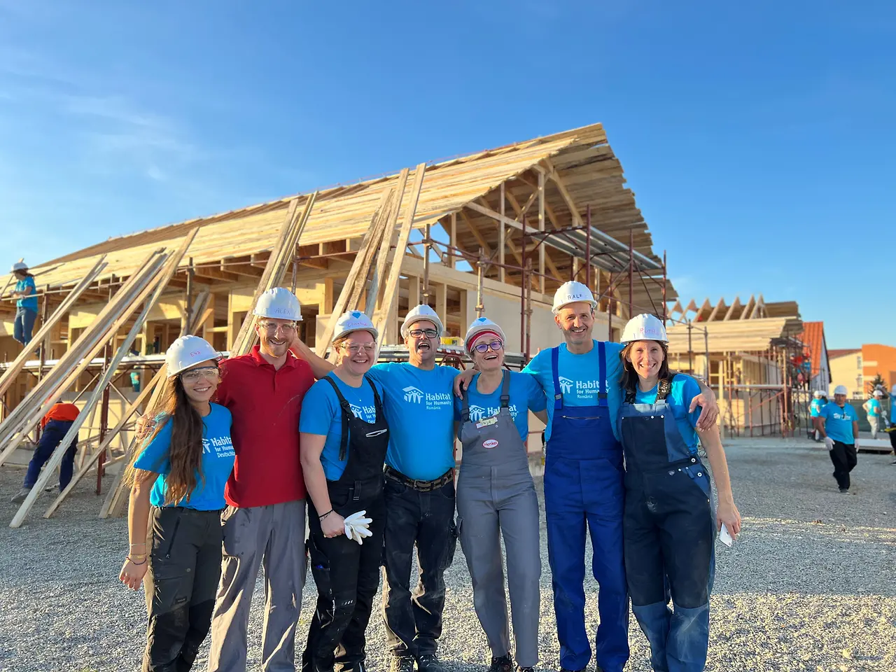 Voluntarios abrazados frente a construcción